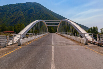 Bridge with iron arches across the river in the mountains