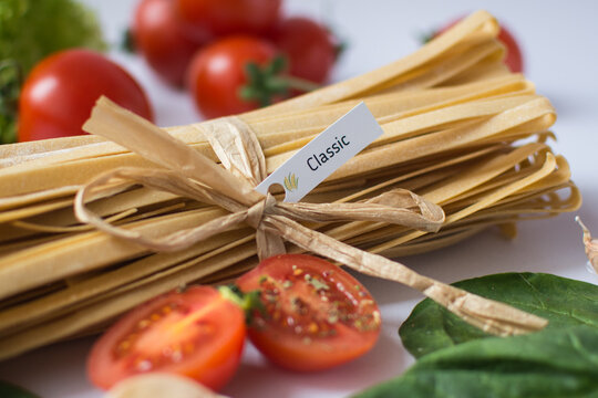 craft handmade pasta with different vegetables : avocado, lettuce leaves, red paprica on the red board