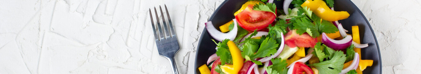 banner of Plate of rainbow salad with different vegetables and herbs on black plate on white stone background