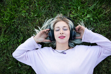 a young blonde woman chilling and enjoying music with headphones