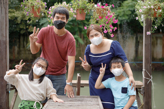 asian family wearing protection face mask hand sign victory in park