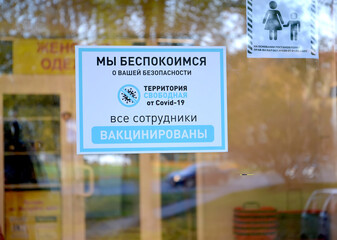 KALININGRAD, RUSSIA. An information poster with the inscription "All employees vaccinated" on the front door of a food supermarket. The epidemic of coronavirus COVID-19. Russian text