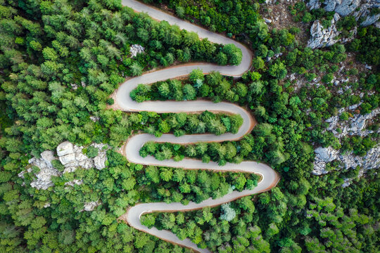 View from above, stunning aerial view of a serpentine road surrounded by green pine trees. Mount Limbara (Monte Limbara) Sardinia, Italy.