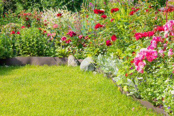A part of the garden area with a variety of perennial flowers and a well-groomed green lawn.