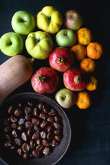 Pan with chestnuts, butternut squash and various fruit on dark background. Flat lay.