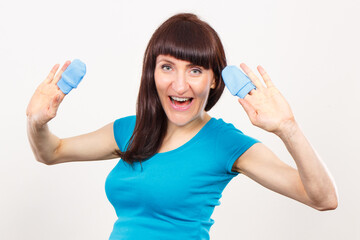 Smiling pregnant woman with blue ribbon on belly holding gloves for baby, expecting for newborn concept