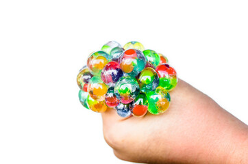 Hand of a girl squeezing a colorful stress ball on white background. Improved motor skills