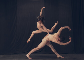 Two flexible dancer, young man and woman in modern art performance isolated on black studio background. Art, motion, inspiration concept.