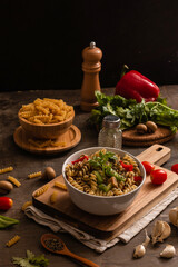 A bowl of fusilli with green peppers and cherry tomatoes