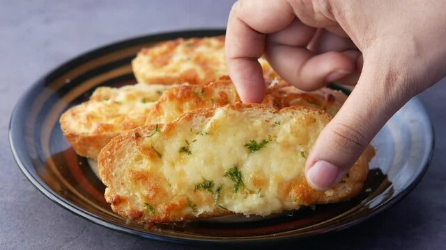 hand pick a garlic bread on a plate 
