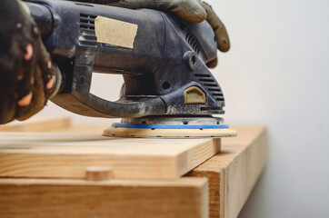 Joiner's tools. Sanding a wooden board with a hand-held electric sander