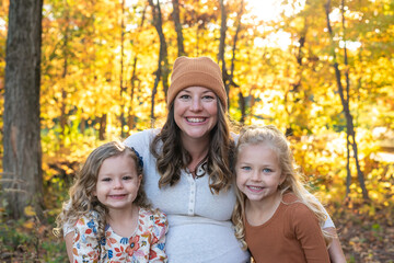 Fototapeta premium Cute young mom and two little girls in autumn at golden hour