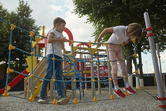 little caucasian children playing at playground. skinny boy and girl having fun outdoors. childhood concept, outdoor activity, sport at school