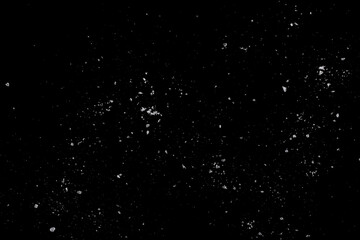 White crystals of salt on a black surface.