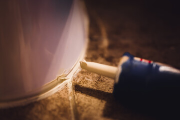 Selective focus on silicone caulking ready to be applied around the seal of a bathroom toilet.