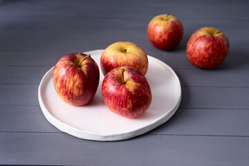 red apples on flat  white plate handmade on a gray wooden table