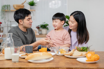 happy family together. Asian parent eating breakfast with little son in the kitchen.