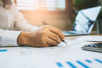 Close up hand of professional accountant review tax paperwork and signing signature on the table in...
