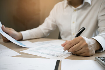 Close up hand of professional accountant review tax paperwork and signing signature on the table in workplace