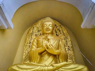 meditating buddha golden statue from low angle at monastery at morning