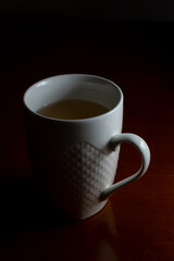 A cup of tea on a wooden table with a dark background