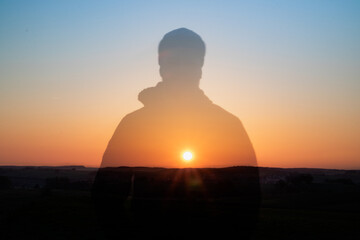 silhouette of a person in the sunrise with the sun shining through