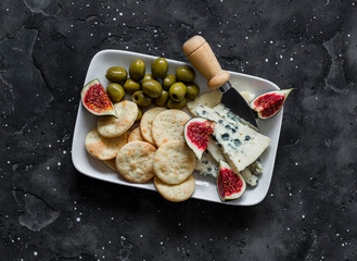 Delicious appetizer plate - blue cheese, olives, homemade cheese cracker, figs on a light marble...