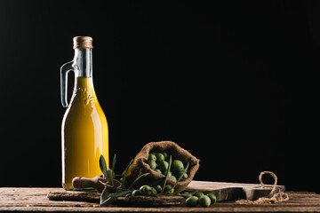 Olive oil with fresh olives on rustic wood