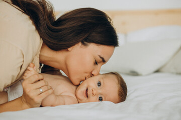 Mother with baby daughter lying on bed