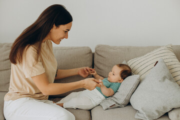 Mother with baby girl on sofa at home