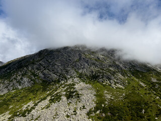 cloud and fog is moving over high mountain peak in summe