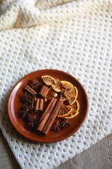 Plate of various winter spices and knitted blanket. Selective focus.