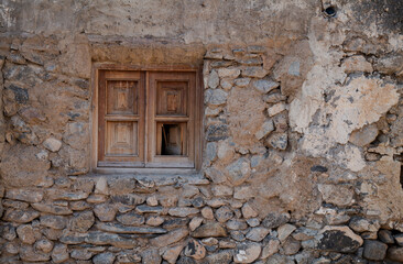 Fototapeta na wymiar Wooden window on stone wall of abandoned building