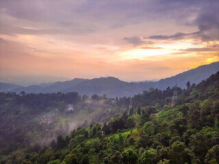 dramatic sunset orange sky over mountain range and green forest at evening from hill top