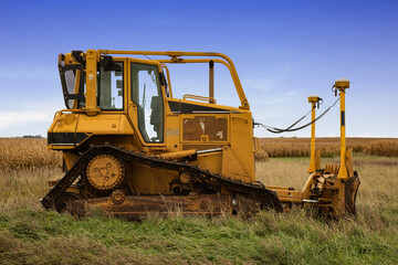 A bulldozer with GPS sitting idle in a farm field.