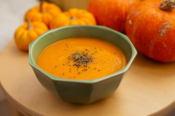 pumpkin soup in a bowl closeup with pumpkins around it