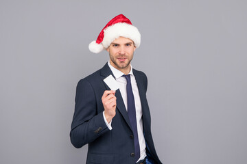 businessman in santa hat hold credit card with copy space on grey background, christmas sale