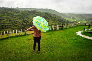 young girl enjoying rain with umbrella at mountain mountain top