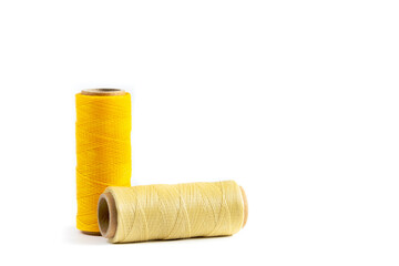 A skein of yellow and beige thread. Coils of colored threads on a white background. Waxed sewing thread for leather goods.