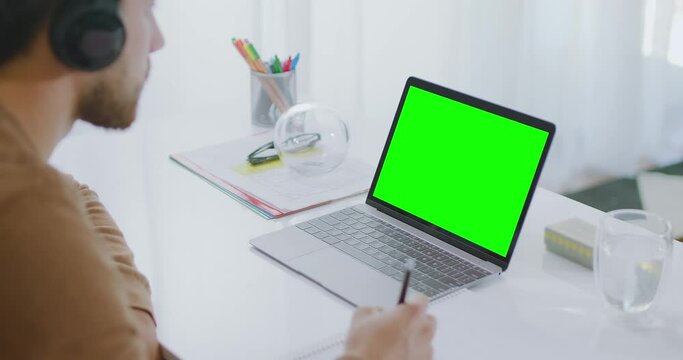 Sequence of Shots of Caucasian Man Using Headsets Working or Studying From Home. Student taking notes and nodding. Close Up of Laptop With Green Screen. Lateral Dolly and Locked Shots.