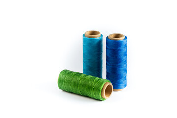 A skein of green, blue and cyan thread. Coils of colored threads on a white background. Waxed sewing thread for leather goods.