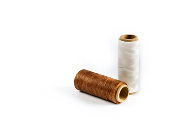 A skein of white and brown thread. Coils of colored threads on a white background. Waxed sewing thread for leather goods.