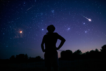 Silhouette of a man enjoying countryside under the starry skies.