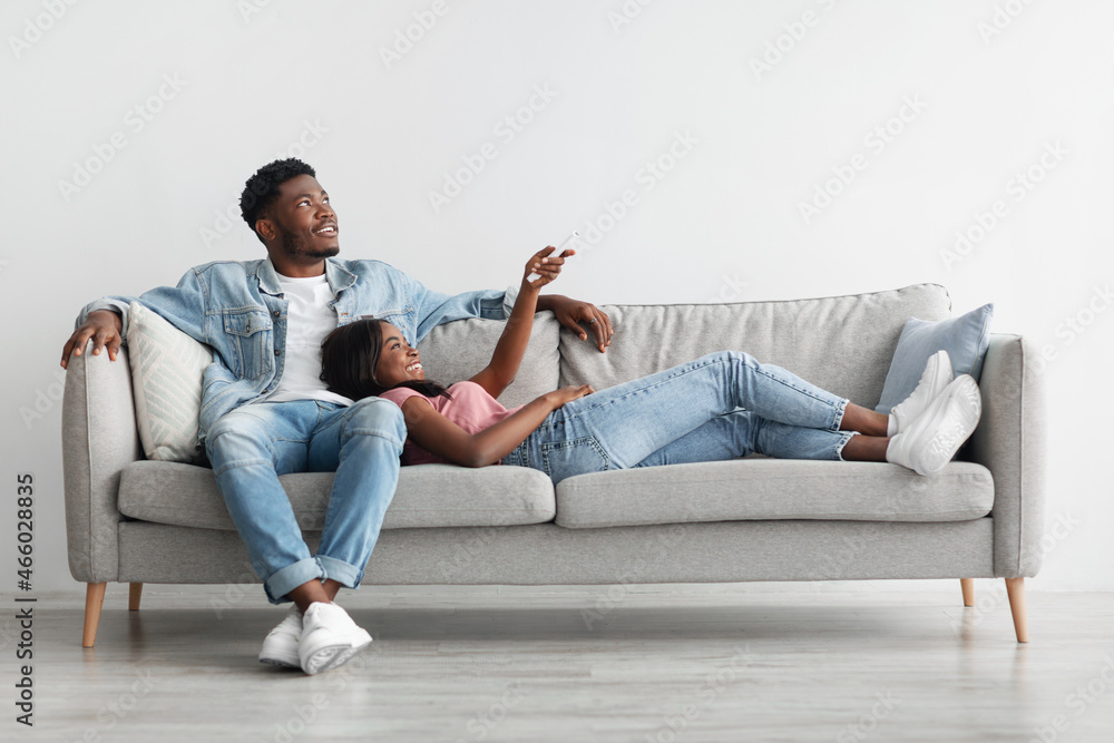 Wall mural Young black woman switching on air conditioning at home