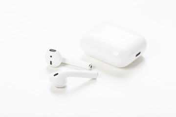 Modern wireless bluetooth headphones with charging case on a light gray background. The concept of...