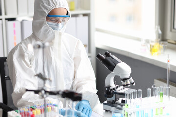 Scientist in protective suit, mask and gloves conducts laboratory research