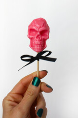 pink lollipop in the shape of a skull on a stick on a white background. the concept of Halloween