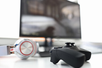 Game joystick with headphones lie on table with computer monitor closeup © megaflopp