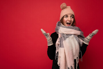 Photo of young positive happy shocked amazed attractive brunette woman with sincere emotions wearing winter clothes isolated over red background with copy space