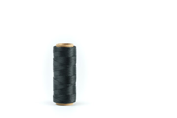 A coil of black thread. Spool of colored threads on a white background. Waxed sewing thread for leather crafts.